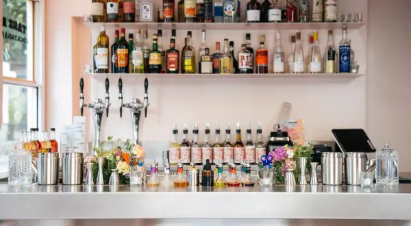 Bar à cocktails prêt à servir, avec des bouteilles d'alcool sur les étagères et des sirops colorés sur le comptoir. Les "bisous bisous club reviews" sont excellentes pour ce bar !