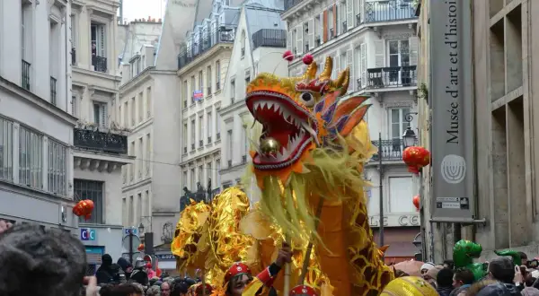 Un grand dragon doré danse dans les rues de Paris lors du défilé du nouvel an chinois, sous les regards émerveillés de la foule.
