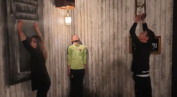 Trois personnes dans une pièce aux murs décrépits, défiant la gravité. Une femme s'accroche à un mur, un homme flotte, un autre escalade une chaise. Ambiance de **the dark dreams Paris**.