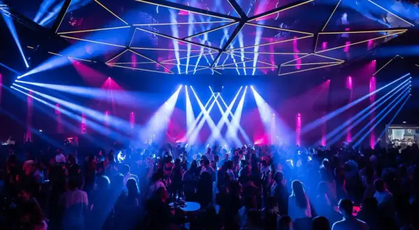 Une foule danse sous des jeux de lumière bleus et roses dans une salle de concert, évoquant l'ambiance d'un "phantom Paris" nocturne.