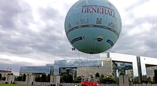 Ballon dirigeable "Générali" survolant Paris, avec la Mairie de Paris et Air Parif inscrits sur sa surface.