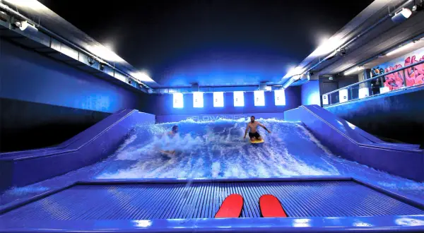Surf sur une vague artificielle à Paris pour des sensations fortes. Deux personnes s'amusent sur la planche.
