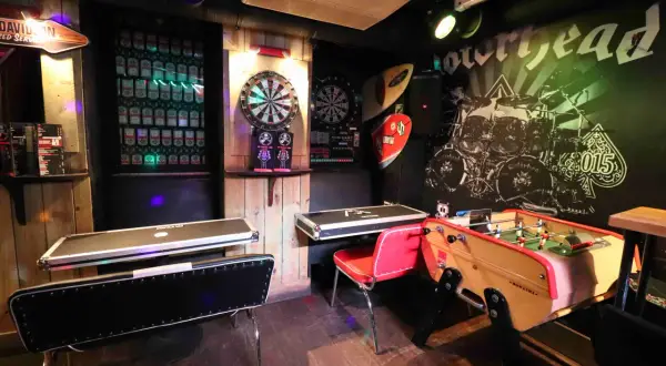 Ambiance de baby bar avec fléchettes, baby-foot et murs décorés de vinyles rock.