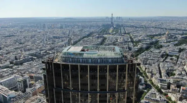 Vue aérienne de Paris depuis la **Tour Montparnasse**. Des visiteurs profitent de la vue panoramique sur la ville, avec la Tour Eiffel en toile de fond.