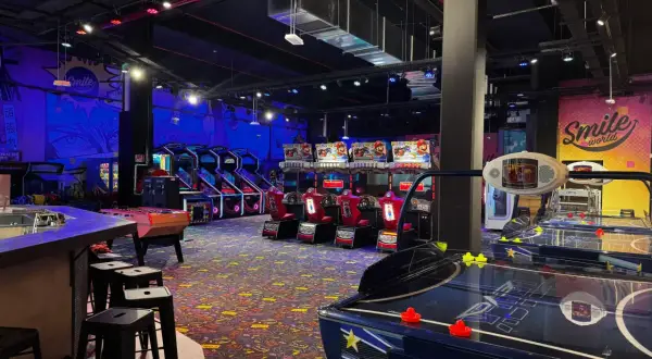 Ambiance de fête foraine à Montparnasse, avec des jeux d'arcade, des tables de air hockey et des murs décorés "Smile world".
