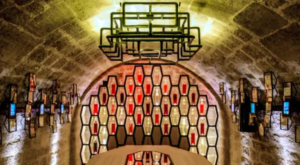 Ambiance unique aux Caves du Louvre, avis sur ce lieu historique et moderne. Bouteilles illuminées dans des alvéoles, table centrale.