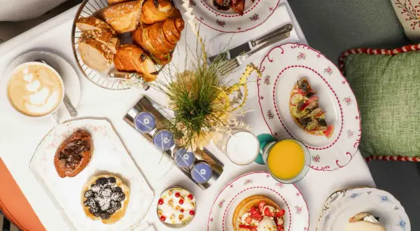 Un plateau de viennoiseries, tartes, œufs, jus et café pour un meilleur brunch parisien.