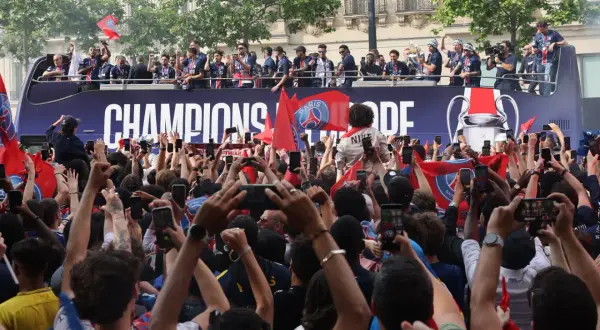 Foule en liesse à Paris, le 14 juillet, pour célébrer les champions sur un bus à impériale. Les téléphones sont levés pour immortaliser l'instant.