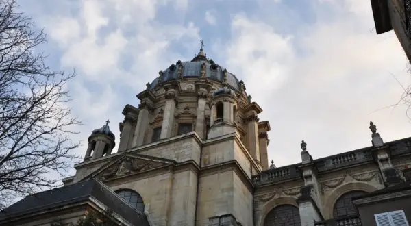 Dôme majestueux de l'église du Val-de-Grâce, se détachant sur un ciel nuageux. L'architecture baroque est impressionnante.
