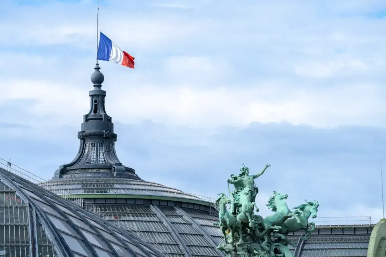 Le drapeau français flotte au sommet d'une tour du palais des congrès Paris, à côté d'une statue de quadrige.