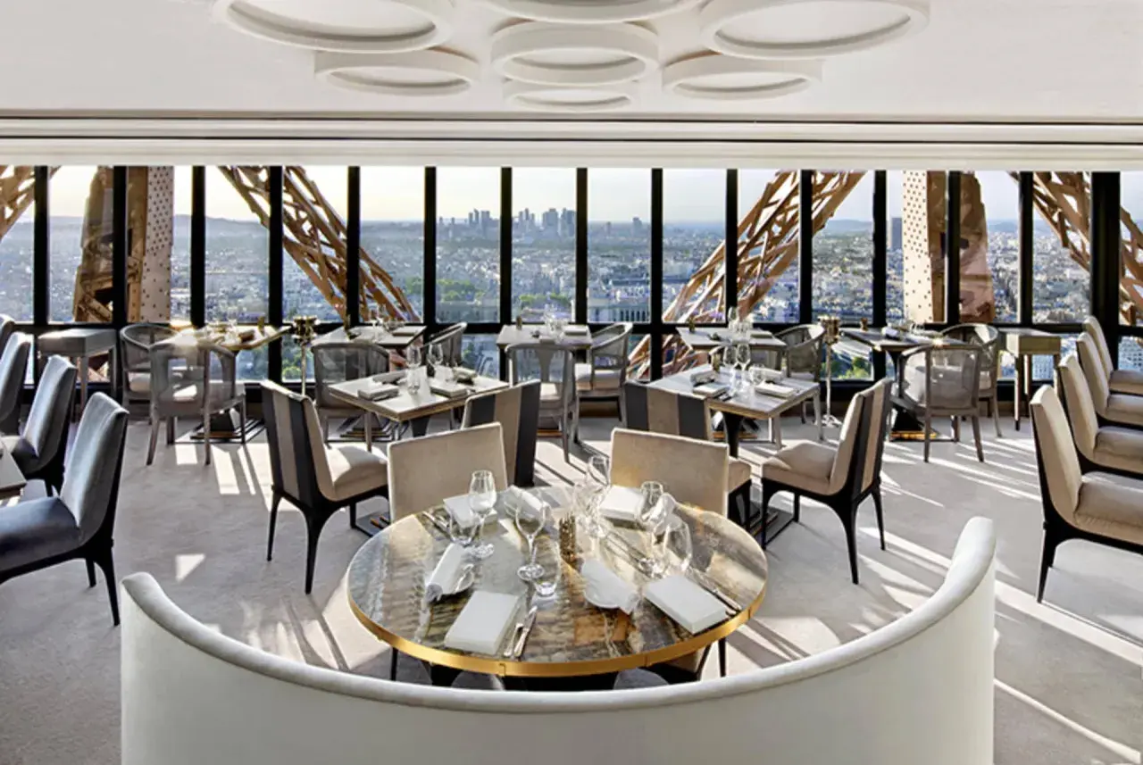 Un restaurant cool pour ado avec vue panoramique sur Paris. Tables dressées, sièges confortables, ambiance chic.
