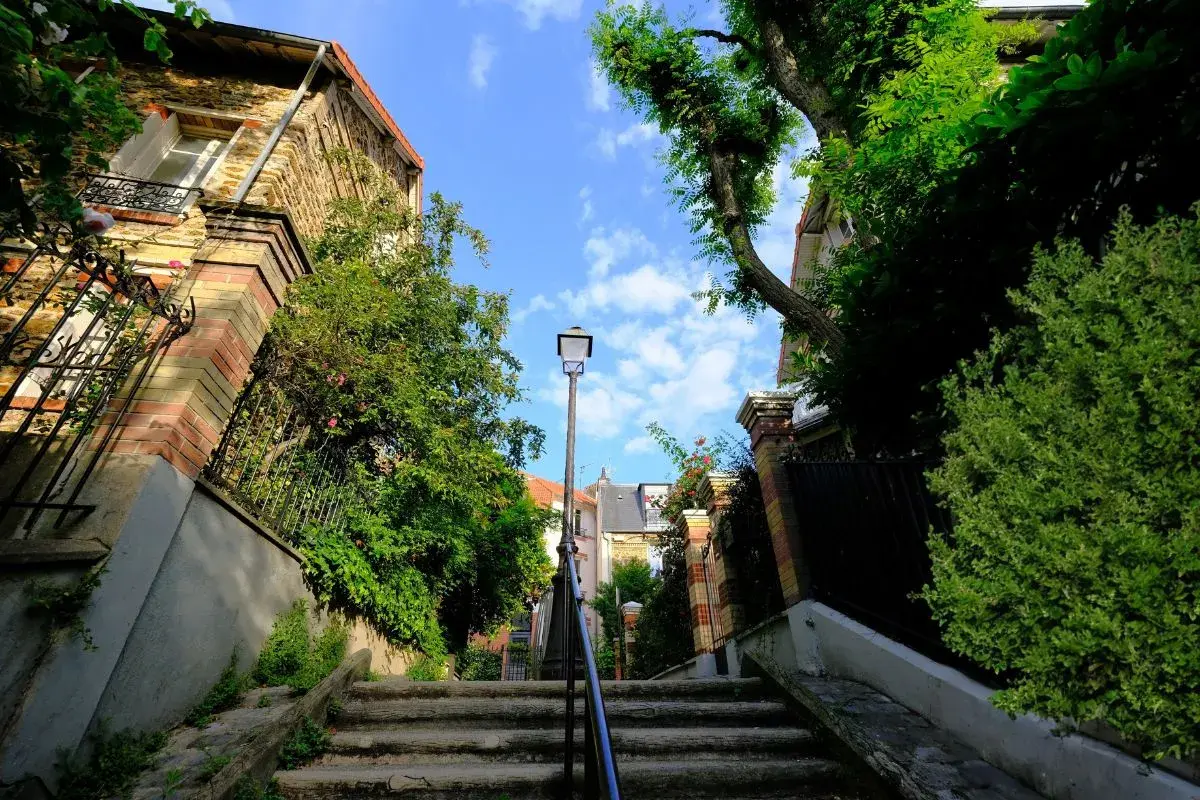 Escalier verdoyant à Paris, une invitation à une activité insolite loin des foules. Un chemin secret sous le ciel bleu.
