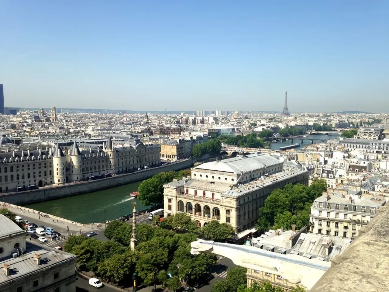 Vue panoramique de Paris, zone 1 à 3, avec la Seine, des bâtiments historiques et la Tour Eiffel au loin.