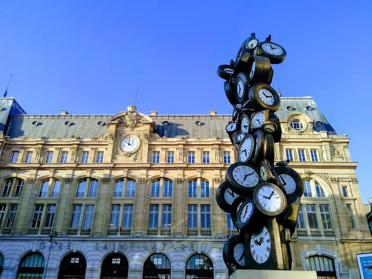Sculpture de multiples horloges devant la gare Saint-Lazare, un monument parisien où le temps s'est arrêté.