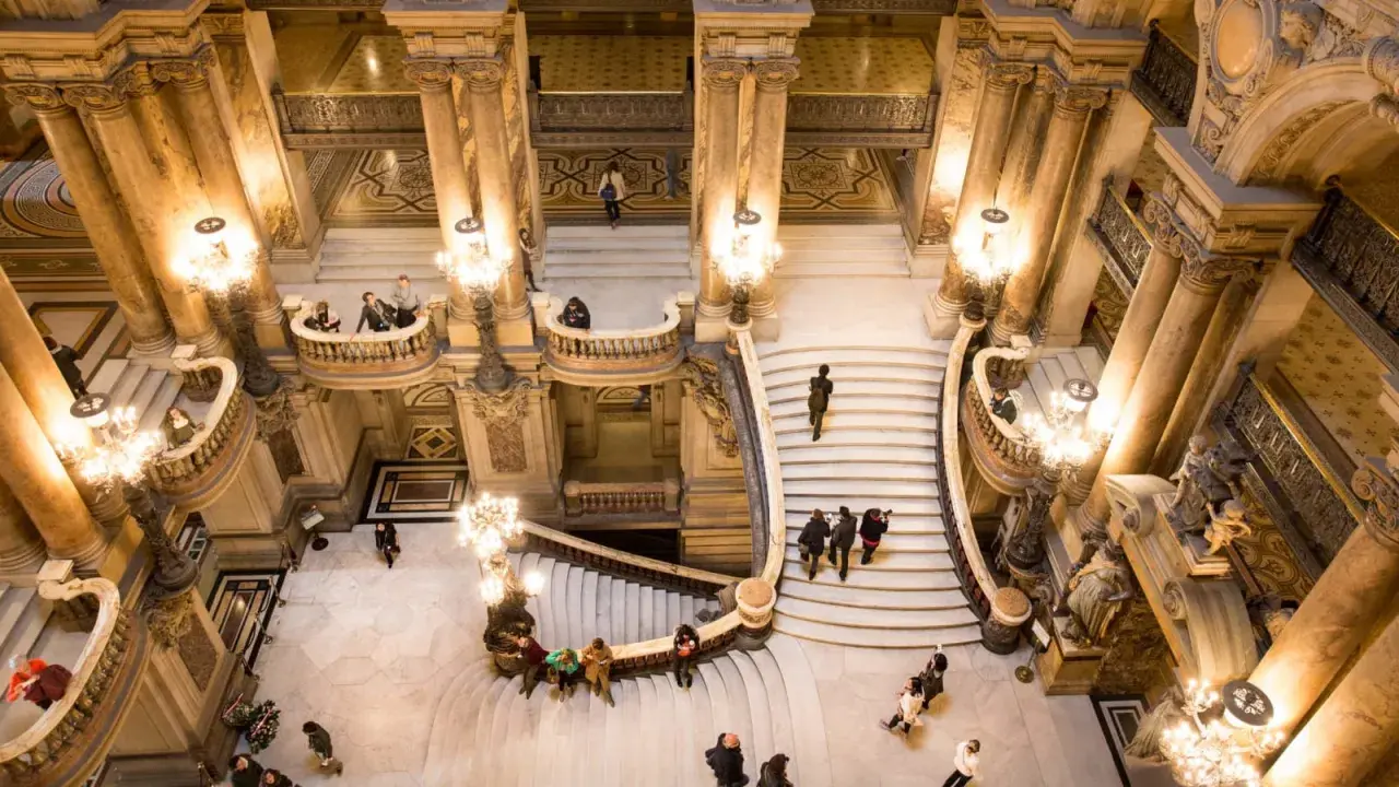Vue aérienne de l'escalier monumental du Palais Garnier avec des visiteurs.