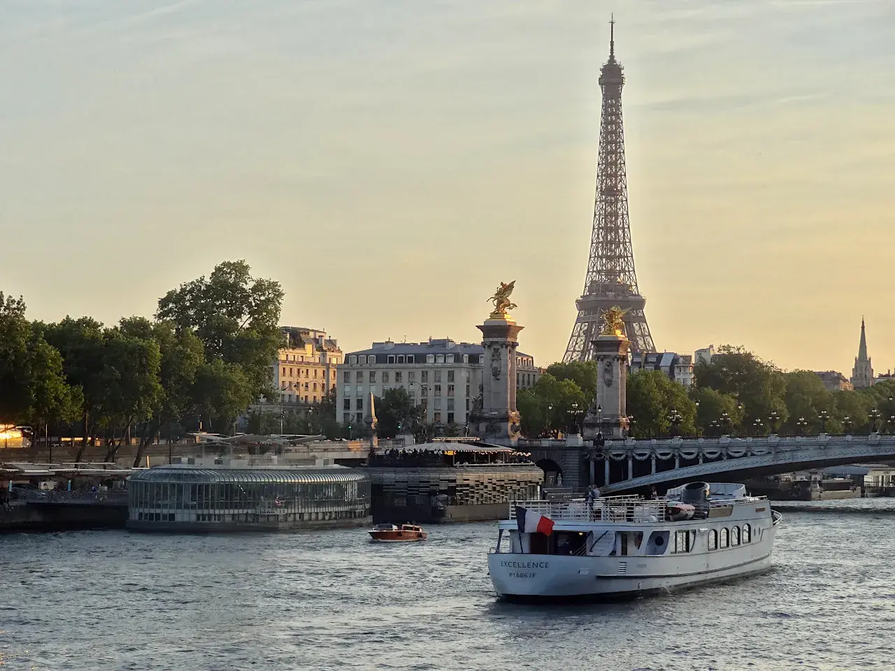 Une belle balade sur Seine à Paris, avec la Tour Eiffel et le pont Alexandre III en arrière-plan. Un bateau navigue paisiblement sur l'eau.