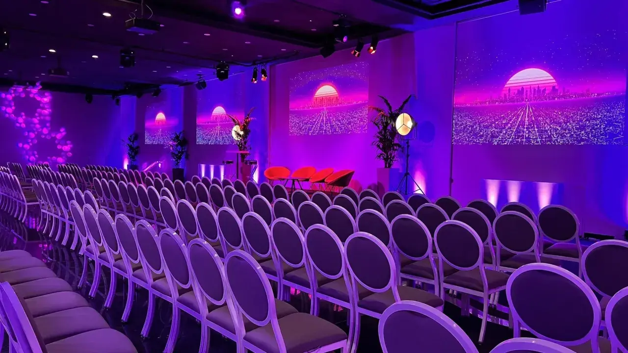Un auditorium à Paris, baigné de lumières violettes, prêt pour un événement futuriste. Des rangées de chaises attendent les invités.