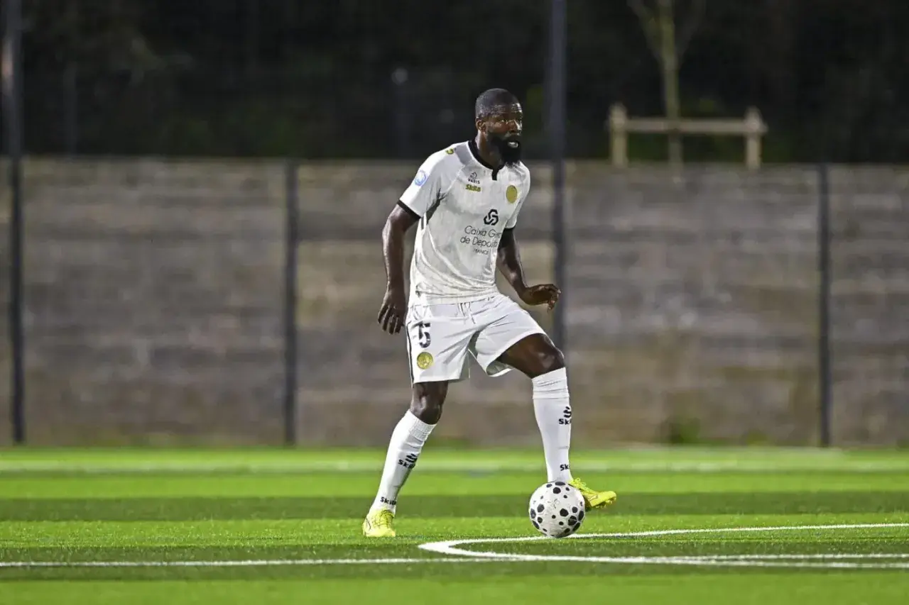 Joueur de football en action sur la pelouse du stade Charléty, concentré sur le ballon.