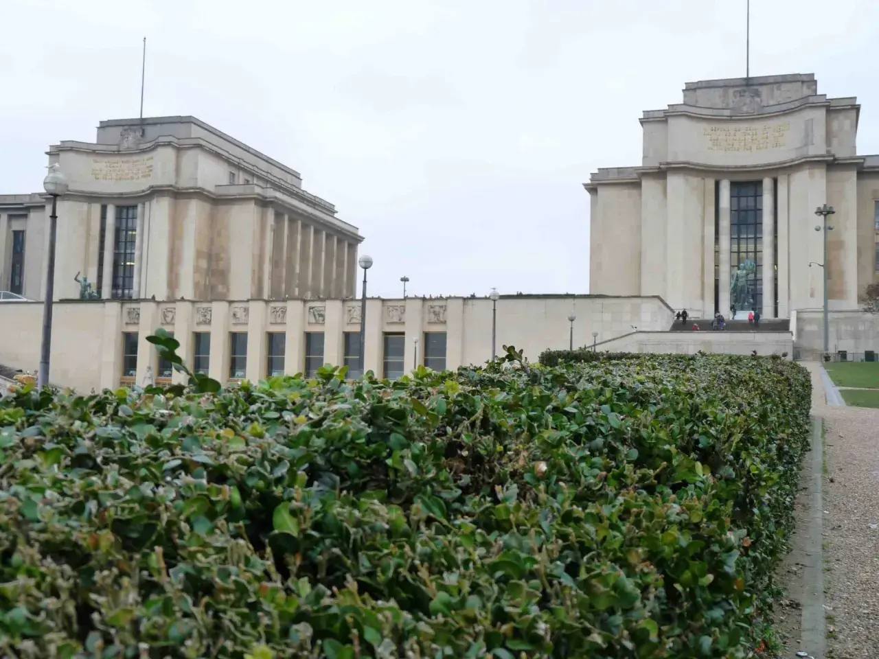 Le **Palais de Chaillot** à Paris, avec ses deux ailes symétriques et sa végétation luxuriante au premier plan.