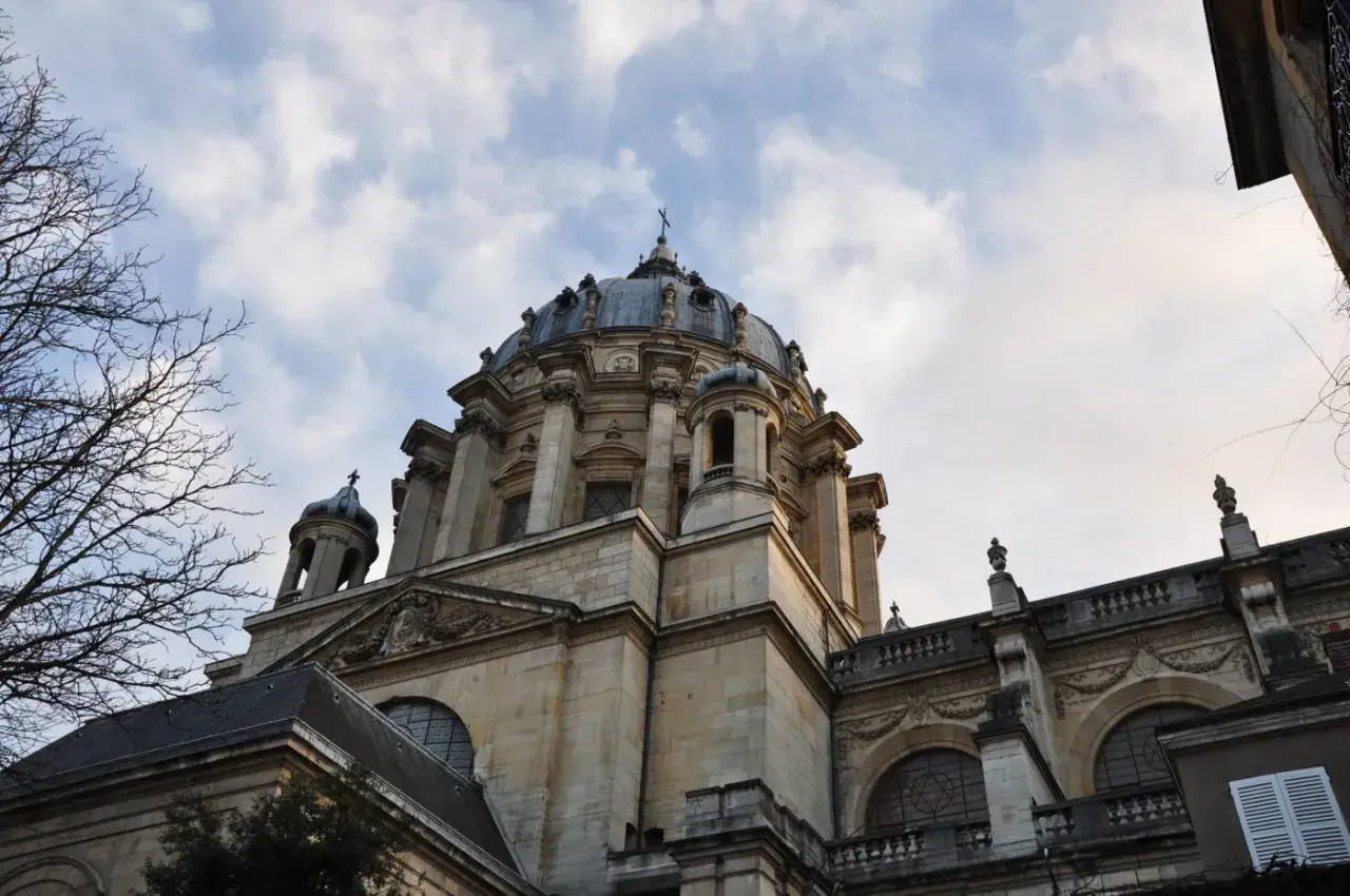 Dôme majestueux de l'église du Val-de-Grâce, se détachant sur un ciel nuageux. L'architecture baroque est impressionnante.