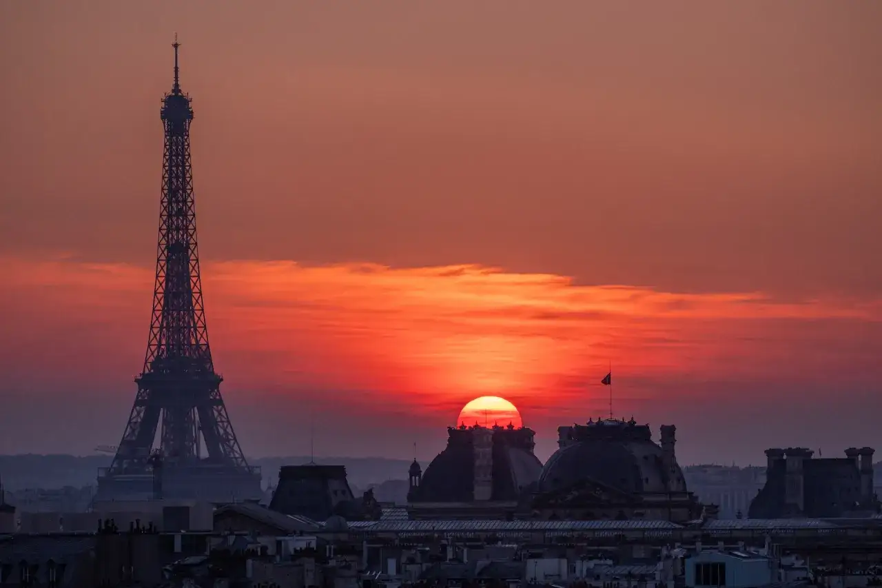 Coucher de soleil spectaculaire sur Paris, avec la Tour Eiffel et les toits de la ville. Idéal pour admirer depuis les meilleurs rooftop bars Paris.