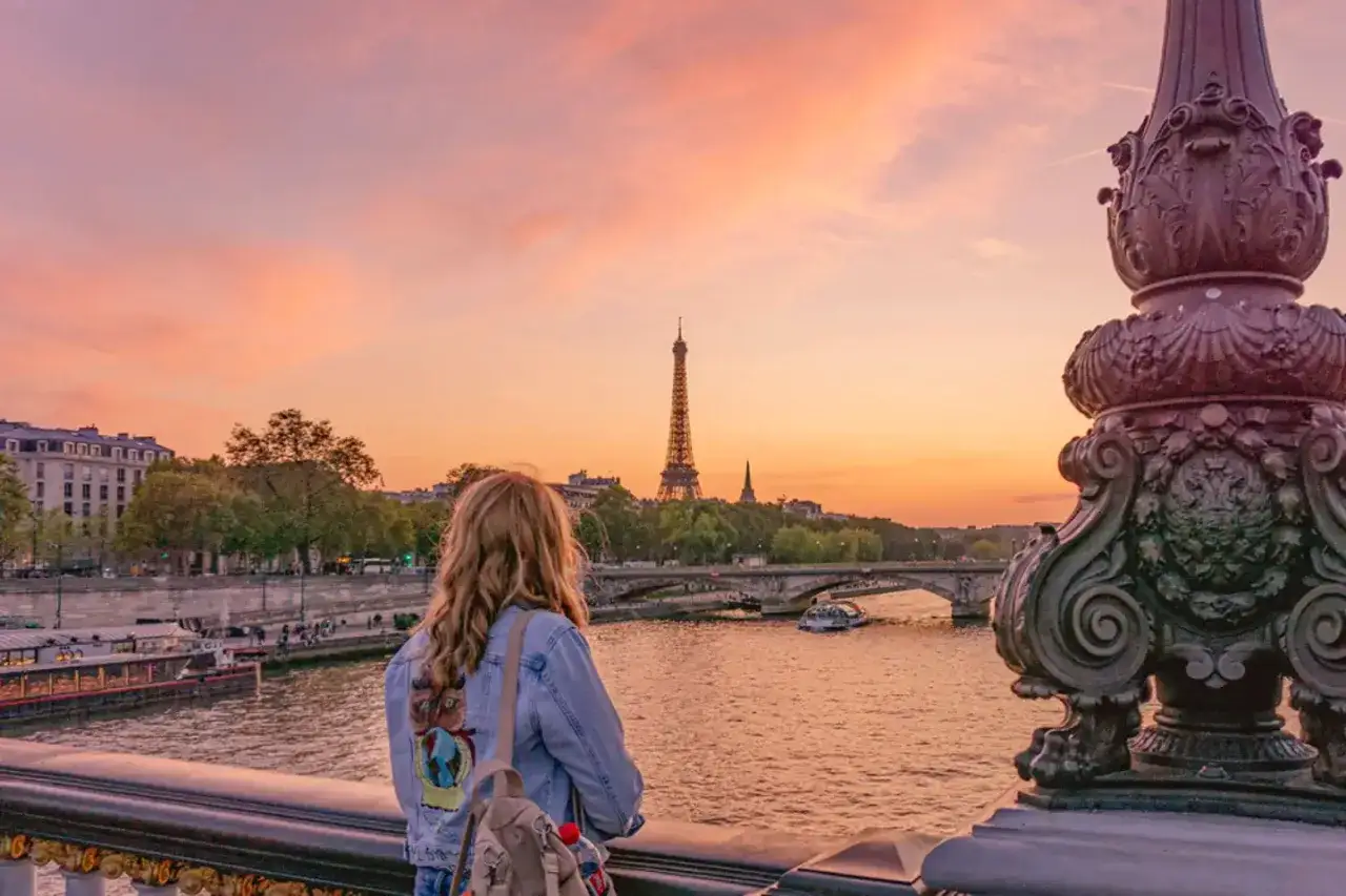 Une jeune femme admire le coucher de soleil sur la Seine, un moment magique parmi les activités à Paris.