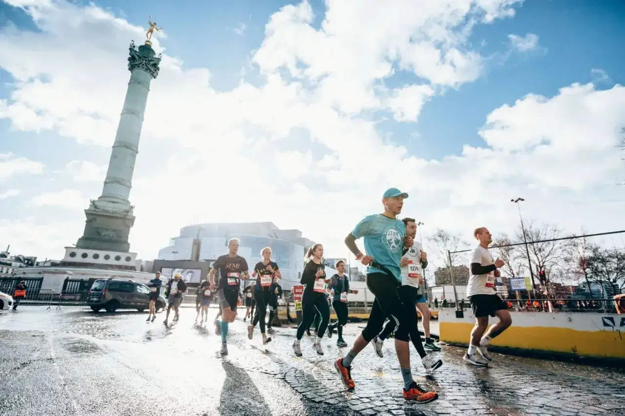 Coureurs en plein effort lors du semi marathon Paris 2026, avec la colonne de Juillet en arrière-plan.