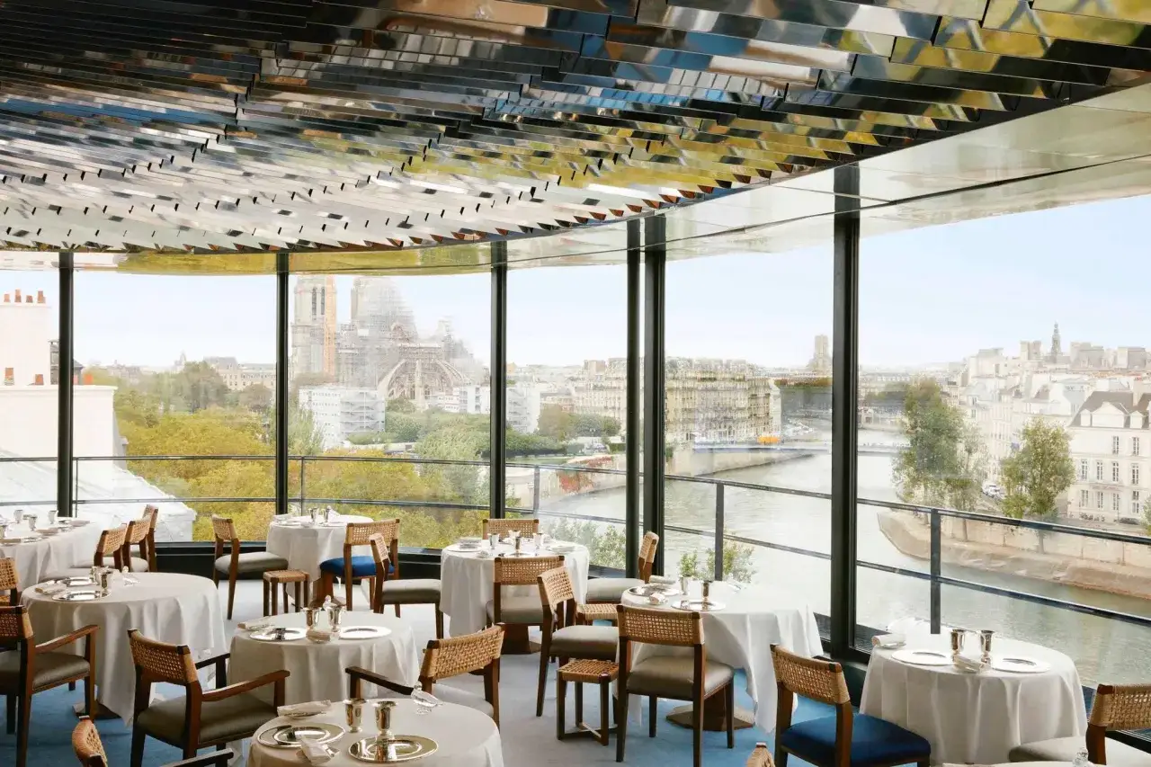 Tables dress&eacute;es pour un d&icirc;ner romantique &agrave; Paris, avec vue sur la Seine et Notre-Dame.