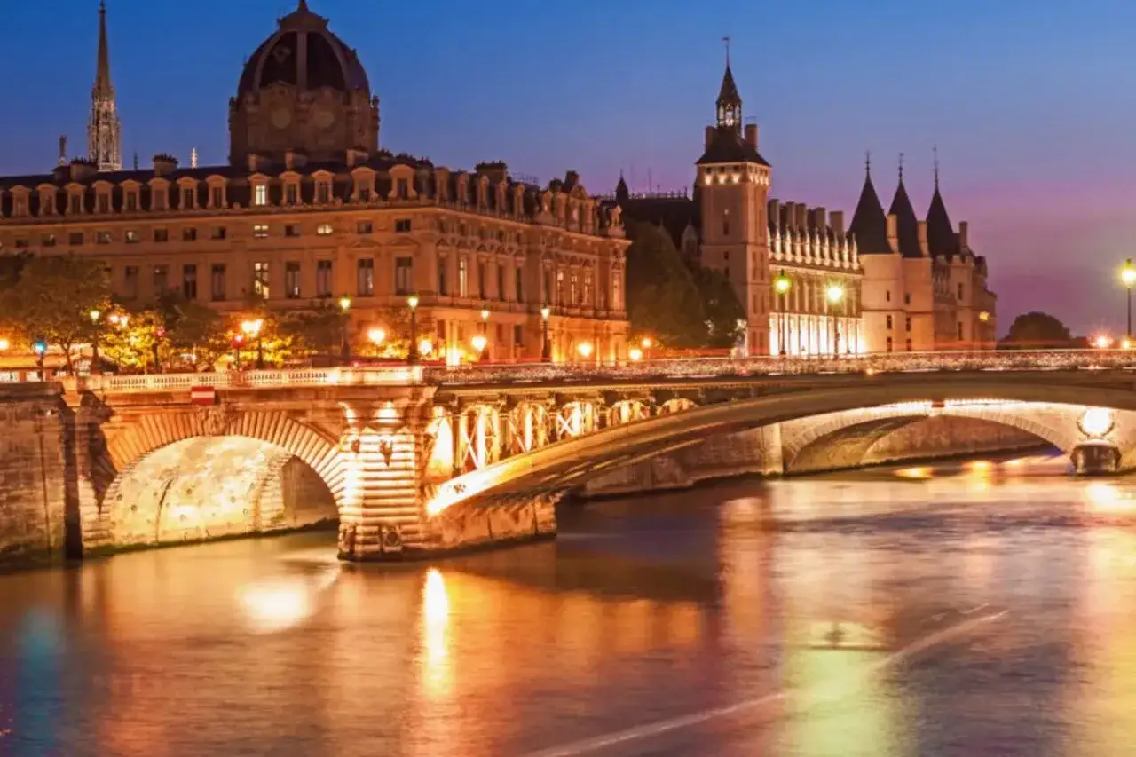 Pont Neuf illumin&eacute;, un incontournable pour un circuit touristique Paris &agrave; pied. La Seine refl&egrave;te les lumi&egrave;res de la ville.