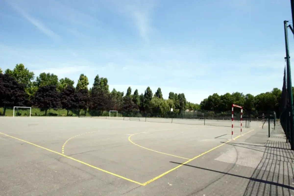Terrain de sport ext&eacute;rieur avec des buts de football et de handball, id&eacute;al pour une partie de five Paris 18.