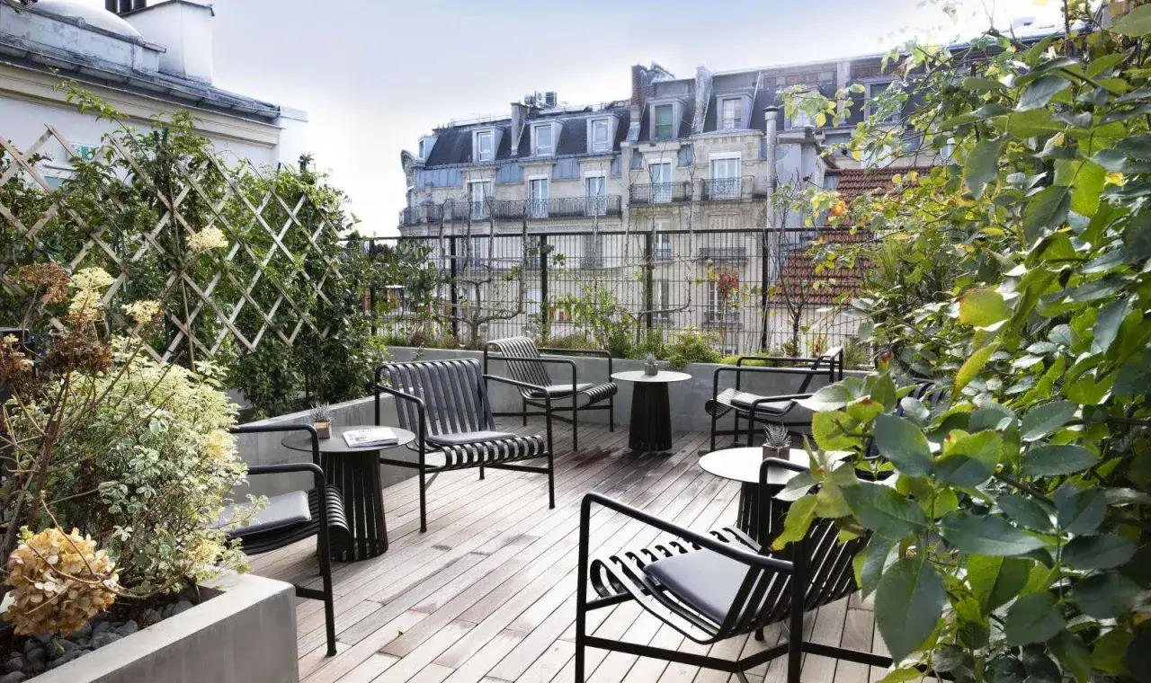 Terrasse avec mobilier moderne et les belles plantes luxuriantes, offrant une vue sur les toits parisiens.