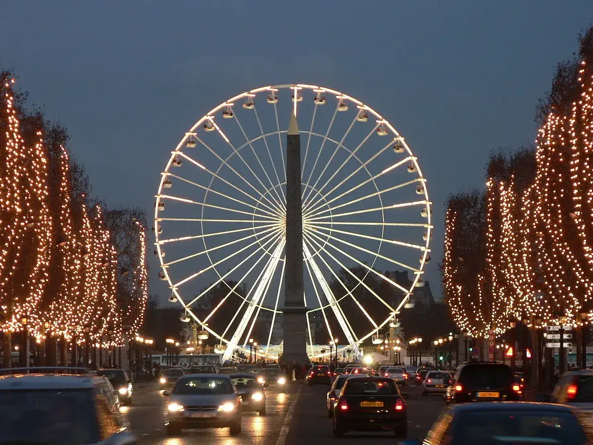 La Grande Roue illumine la nuit parisienne, bordée d'arbres scintillants. Une scène féerique qui rappelle un marché de Noël à Paris.