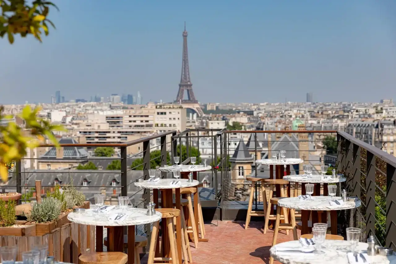 Terrasse avec vue sur Paris, tables dress&eacute;es et la Tour Eiffel en arri&egrave;re-plan. Un perchoir porte de Versailles id&eacute;al pour un d&icirc;ner romantique.