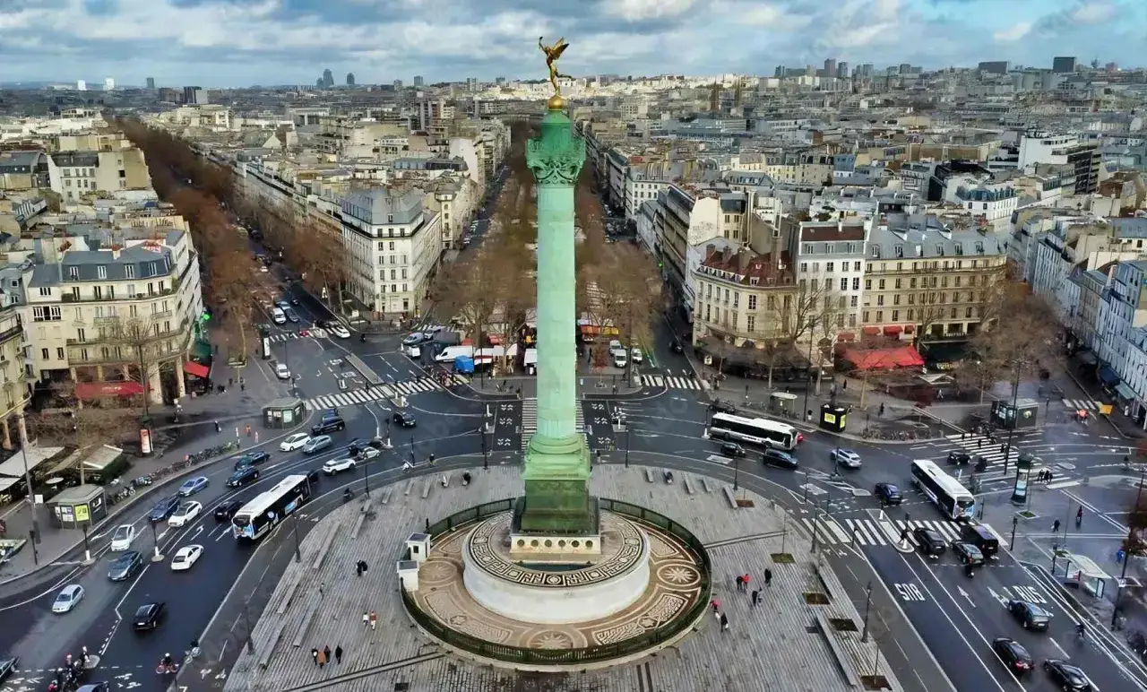 Vue a&eacute;rienne de la colonne de Juillet sur la place de la Bastille, avec circulation et b&acirc;timents parisiens.