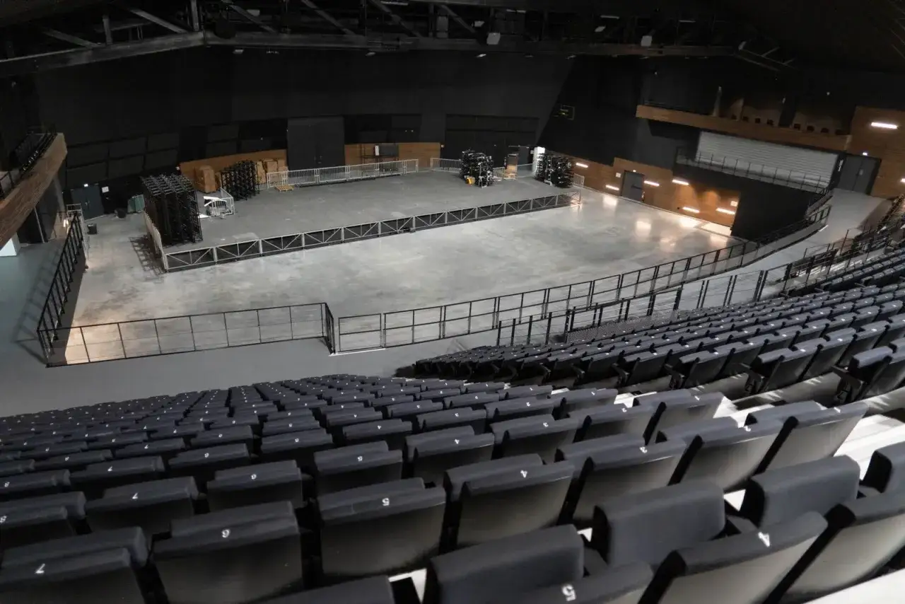 Vue d'une sc&egrave;ne vide dans une arena parisienne, pr&ecirc;te pour un spectacle. Les si&egrave;ges sont rang&eacute;s, attendant le public.