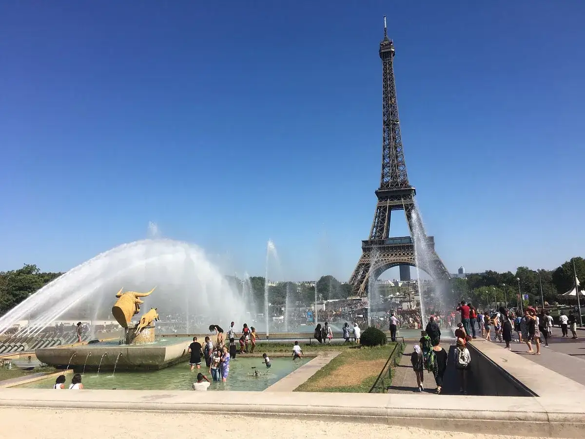 Fontaines spectaculaires devant la Tour Eiffel, avec des visiteurs profitant de l'eau près du Palais de Chaillot.