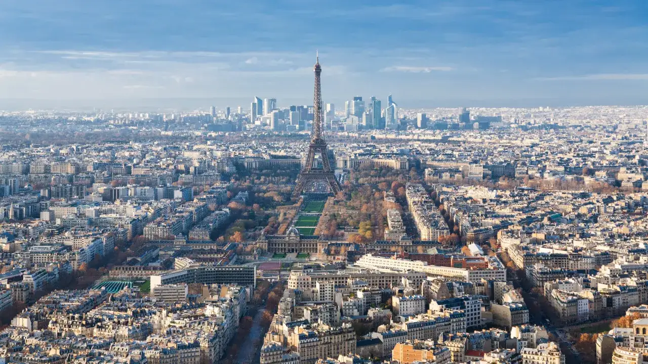 Vue panoramique de Paris depuis l'étage de la Tour Montparnasse, avec la Tour Eiffel au centre et le quartier de La Défense à l'horizon.
