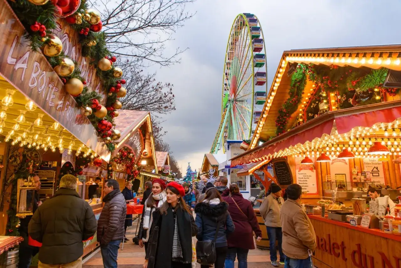 Ambiance f&eacute;erique d'un march&eacute; de No&euml;l en &Icirc;le-de-France, avec ses chalets illumin&eacute;s, sa grande roue et ses visiteurs joyeux.