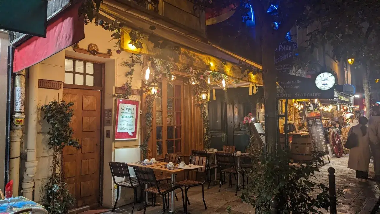 Charmante cr&ecirc;perie illumin&eacute;e la nuit, parfaite pour savoir ou manger apr&egrave;s minuit. Tables dress&eacute;es, lierre et guirlandes lumineuses cr&eacute;ent une ambiance f&eacute;erique.