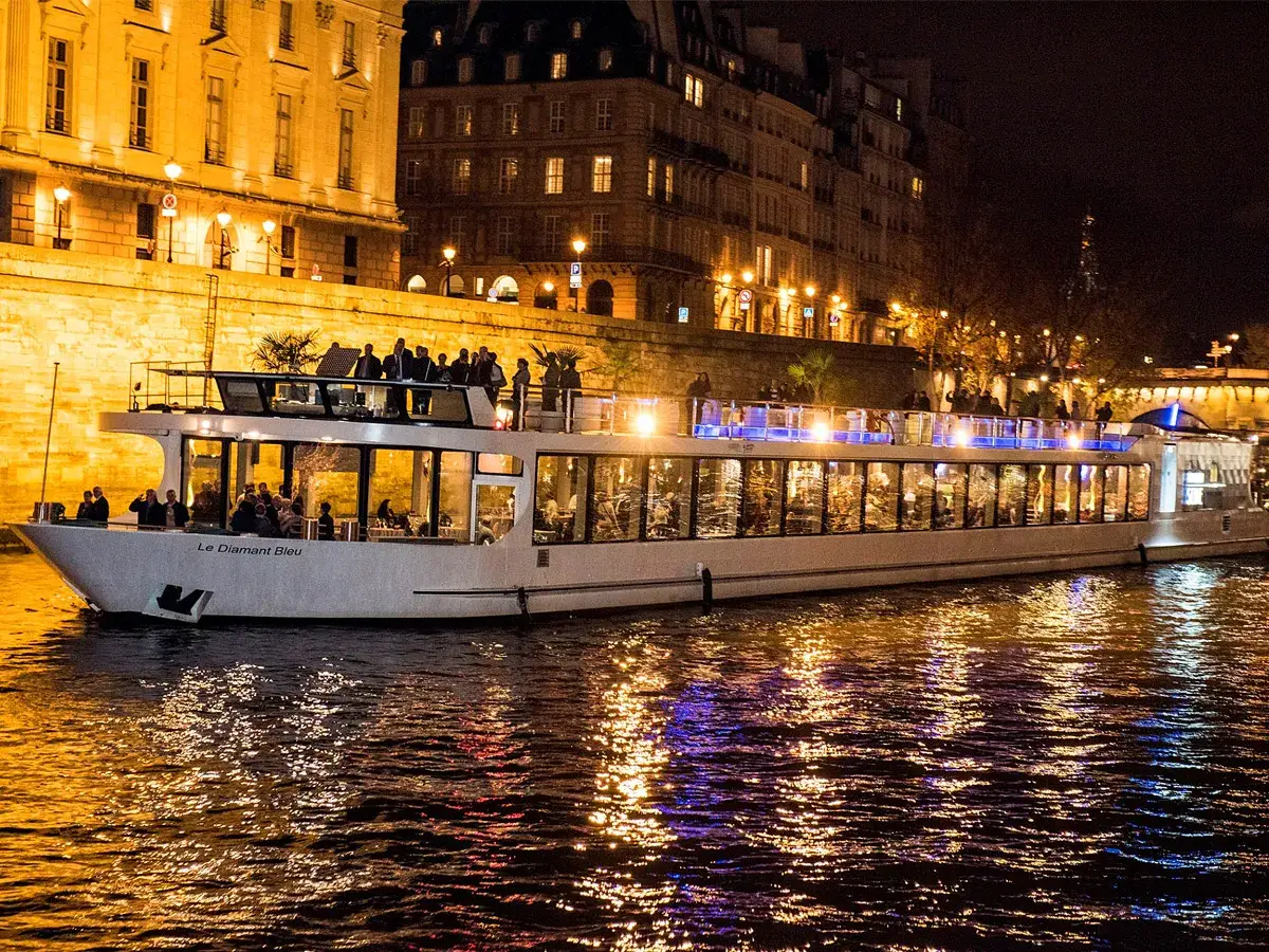 Bateau illuminé sur la Seine, une soirée de réveillon de Noël à Paris. Les reflets dorés dans l'eau créent une ambiance magique.