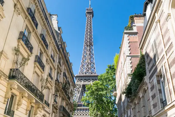 La Tour Eiffel se dresse entre des immeubles parisiens. Un aperçu parfait pour un paris visite pass.