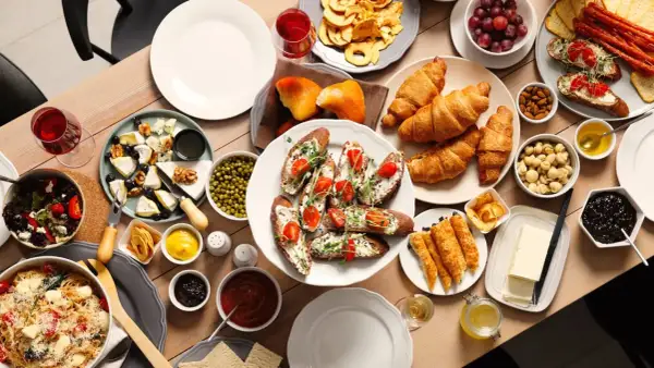 Un délicieux brunch en famille avec croissants, toasts garnis, fromages, fruits et pâtes.
