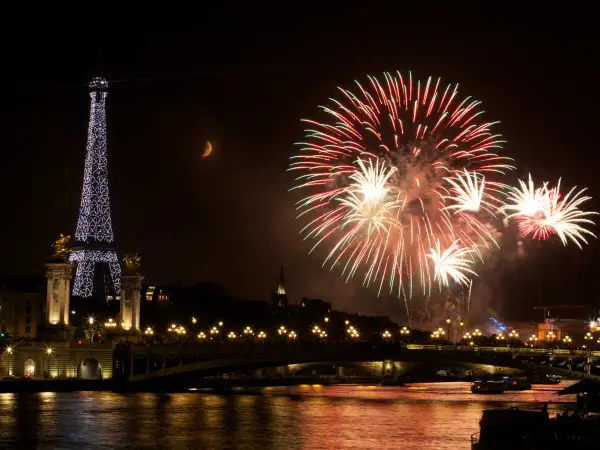 Feux d'artifice spectaculaires illuminent le ciel parisien, avec la Tour Eiffel scintillante et la lune en croissant. Une célébration mémorable pour le 3 avril férié.
