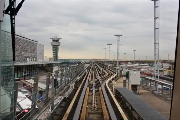 Vue depuis le train automatique Orlyval, avec la tour de contrôle et les voies ferrées. On imagine un voyage vers la Tour Eiffel.
