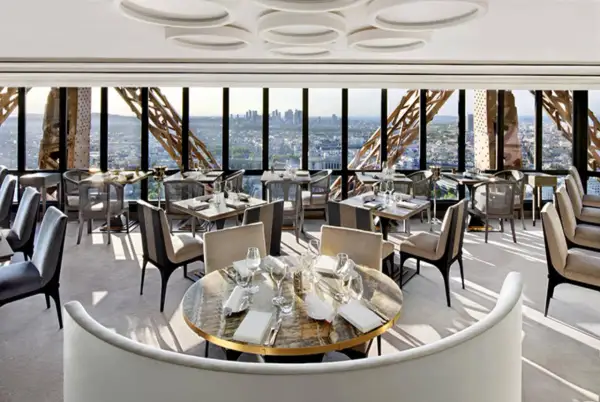 Un restaurant cool pour ado avec vue panoramique sur Paris. Tables dressées, sièges confortables, ambiance chic.