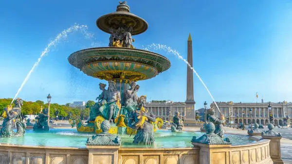 Fontaine monumentale et obélisque sur la place de la Concorde, Paris, sous un ciel bleu éclatant.