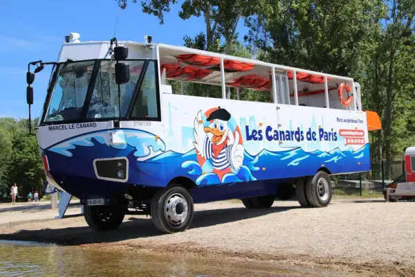 Un bus amphibie décoré de "Les Canards de Paris" avec un canard cartoon, prêt pour une aventure sur l'eau et la terre.