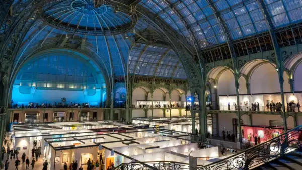 Vue intérieure du Grand Palais à Paris, une exposition d'art se déroule sous sa verrière spectaculaire.
