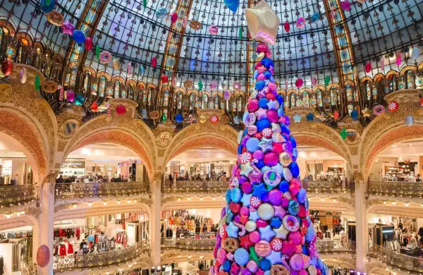 Arbre de Noël féerique fait de bonbons et étoiles, décorations colorées suspendues sous la coupole d'un grand magasin parisien.