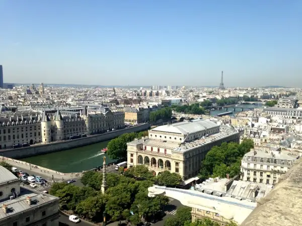 Vue panoramique de Paris, zone 1 à 3, avec la Seine, des bâtiments historiques et la Tour Eiffel au loin.